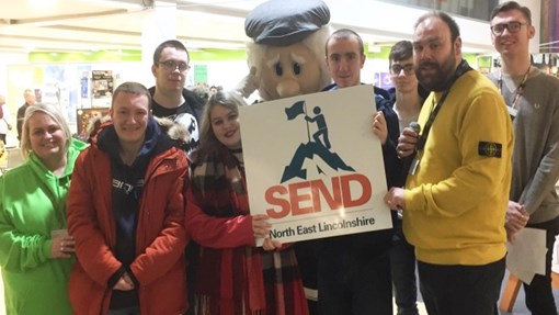 A group of people holding a sign saying SEND
